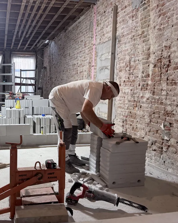 Bouwfoto Newtonstraat 286: een vakman zet de nieuwe binnenwanden