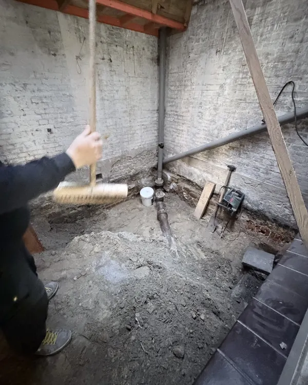 Bouwfoto: een vakman veegt de uitgegraven kruipruimte van Newtonstraat 286 schoon, met het nieuwe riool