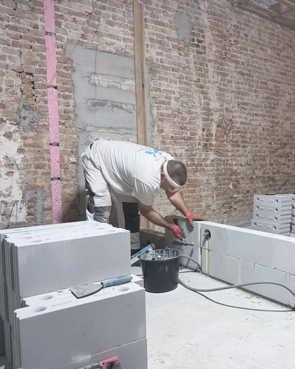 Bouwfoto: een vakman lijmt de nieuwe binnenwanden van Newtonstraat 286